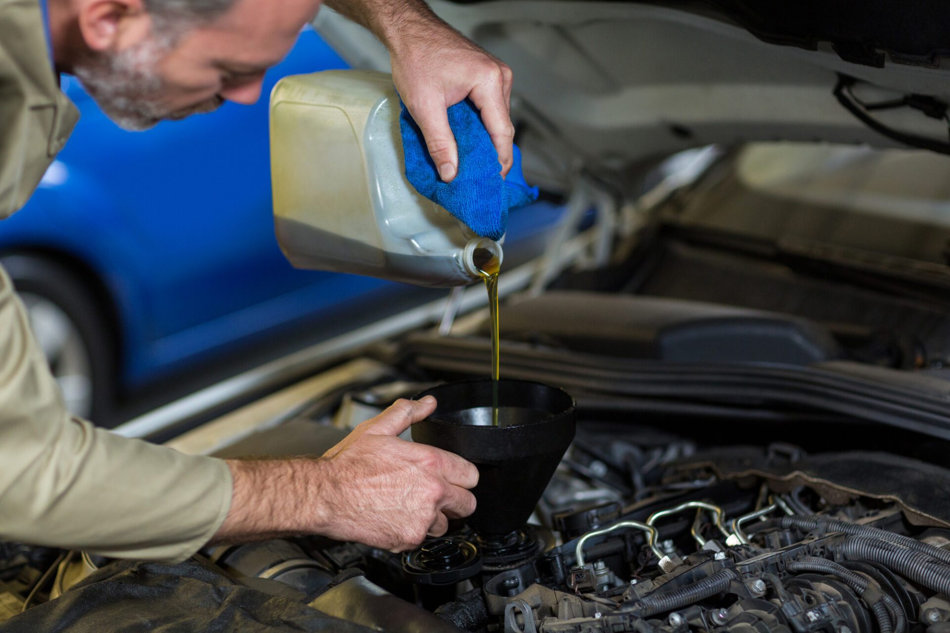 Mechanic pouring oil into car engine<br />
